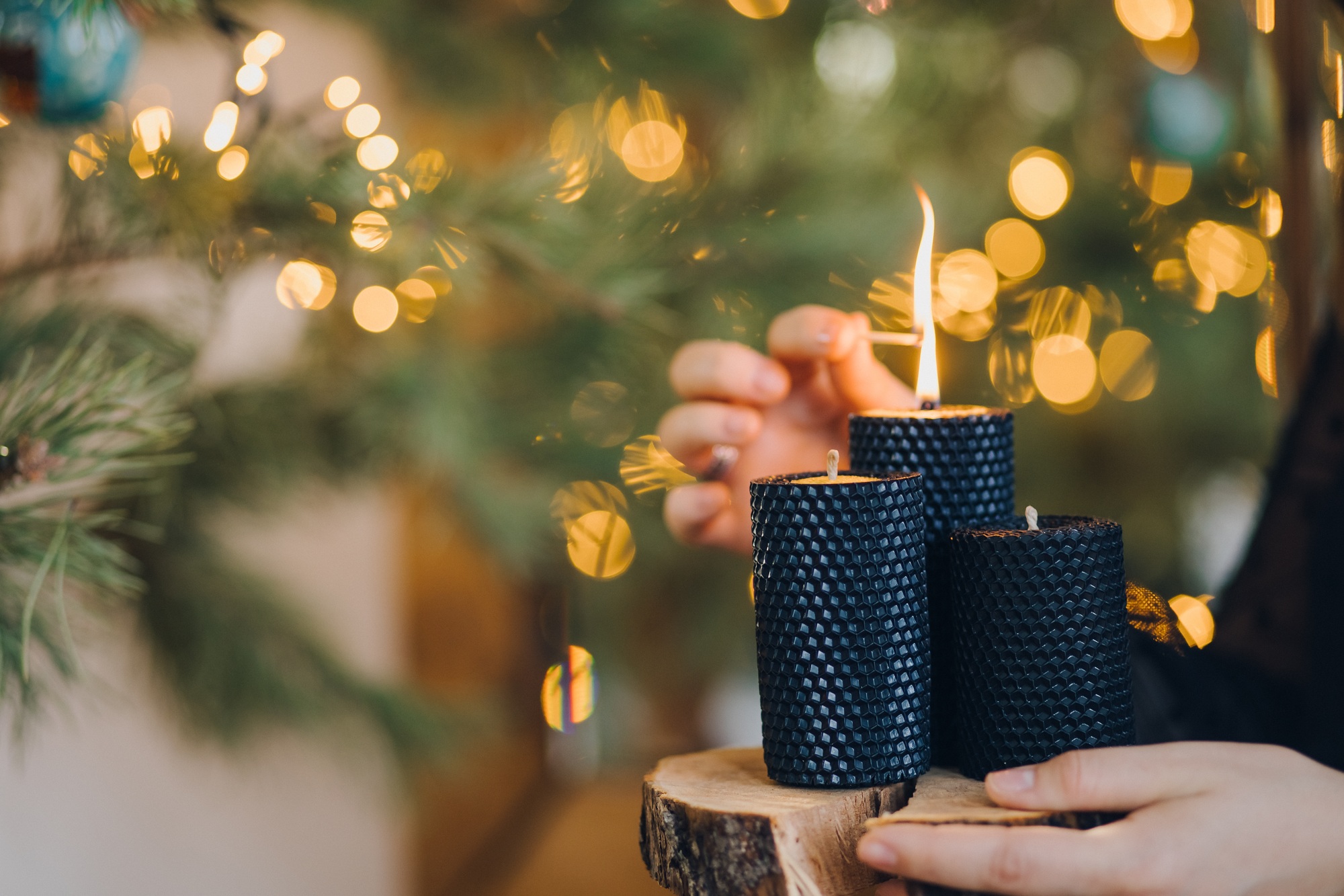 Female hand lighting craft candles on winter holidays time